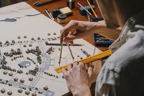 Architect measuring a site plan model with a ruler and compass