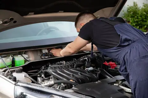 Mechanic leaning into a car's engine bay with tools