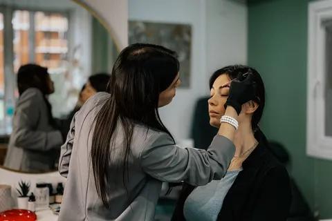 Makeup artist shaping a client’s eyebrows in a salon