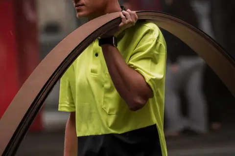 Construction worker in a hi-vis vest carrying materials along a Perth street