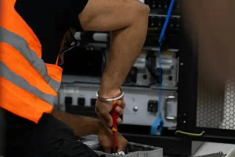 Technician in hi-vis working on network equipment in a rack
