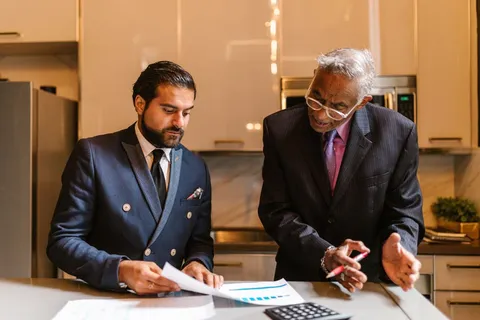 Two advisers in suits reviewing documents with a calculator