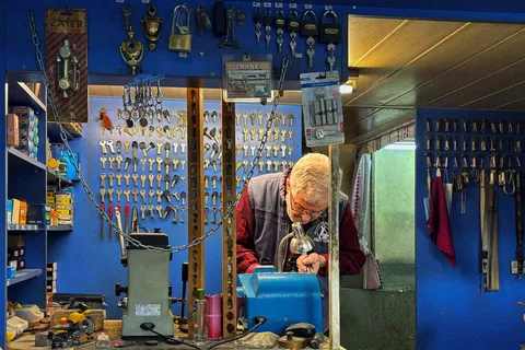 Locksmith cutting keys at the bench in a key shop