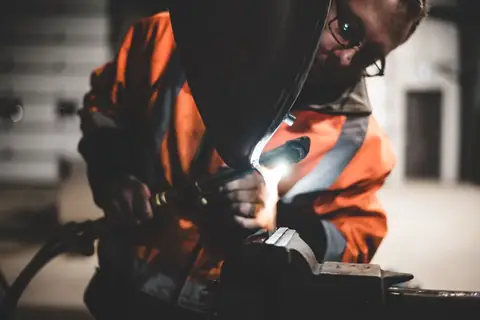 Welder working on metal with sparks flying