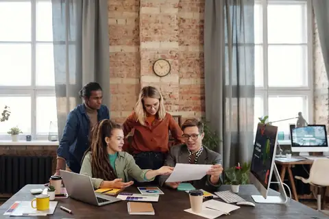 Small team working together around laptops in a brick-walled office
