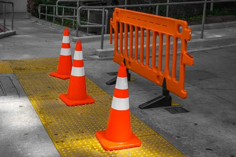 Orange traffic cones and a plastic road barrier on a footpath