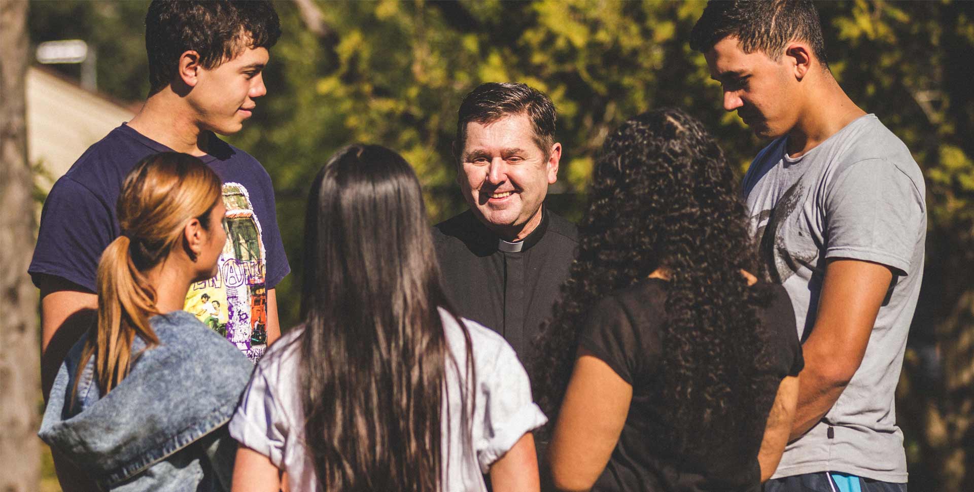 father riley speaking with a group of young people